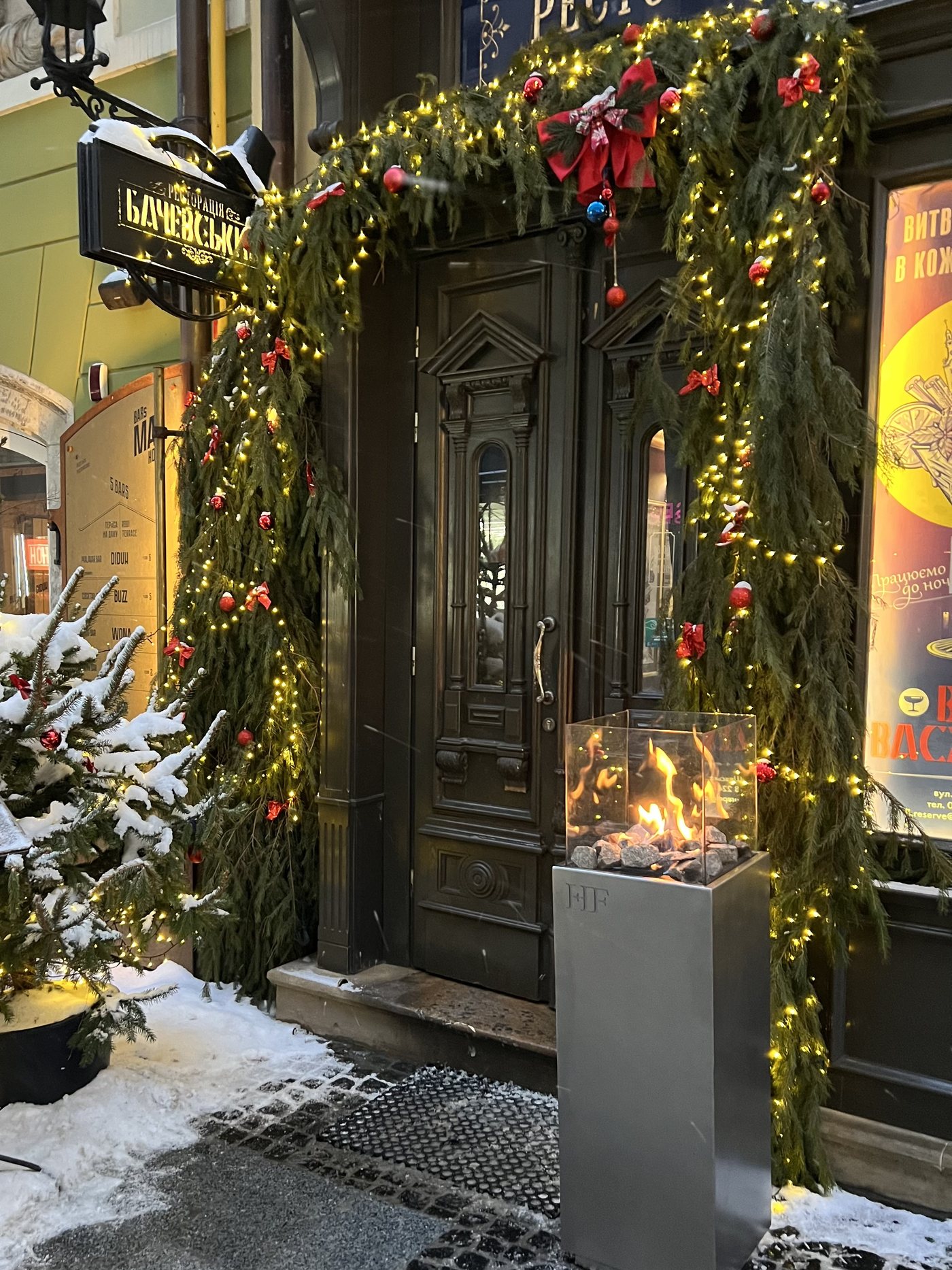 A pair of RODOS fire columns flanking the doors of a restaurant entrance decorated for winter